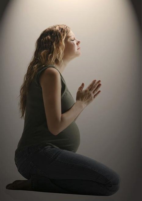 Side view of a pensive pregnant woman sitting in the prayer position